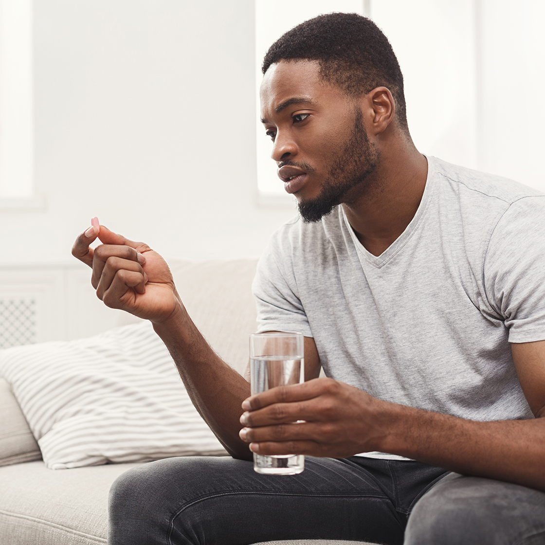 A young man taking a pill, illustrating the use of patient-centred packaging designed for ease and clarity in medication management.