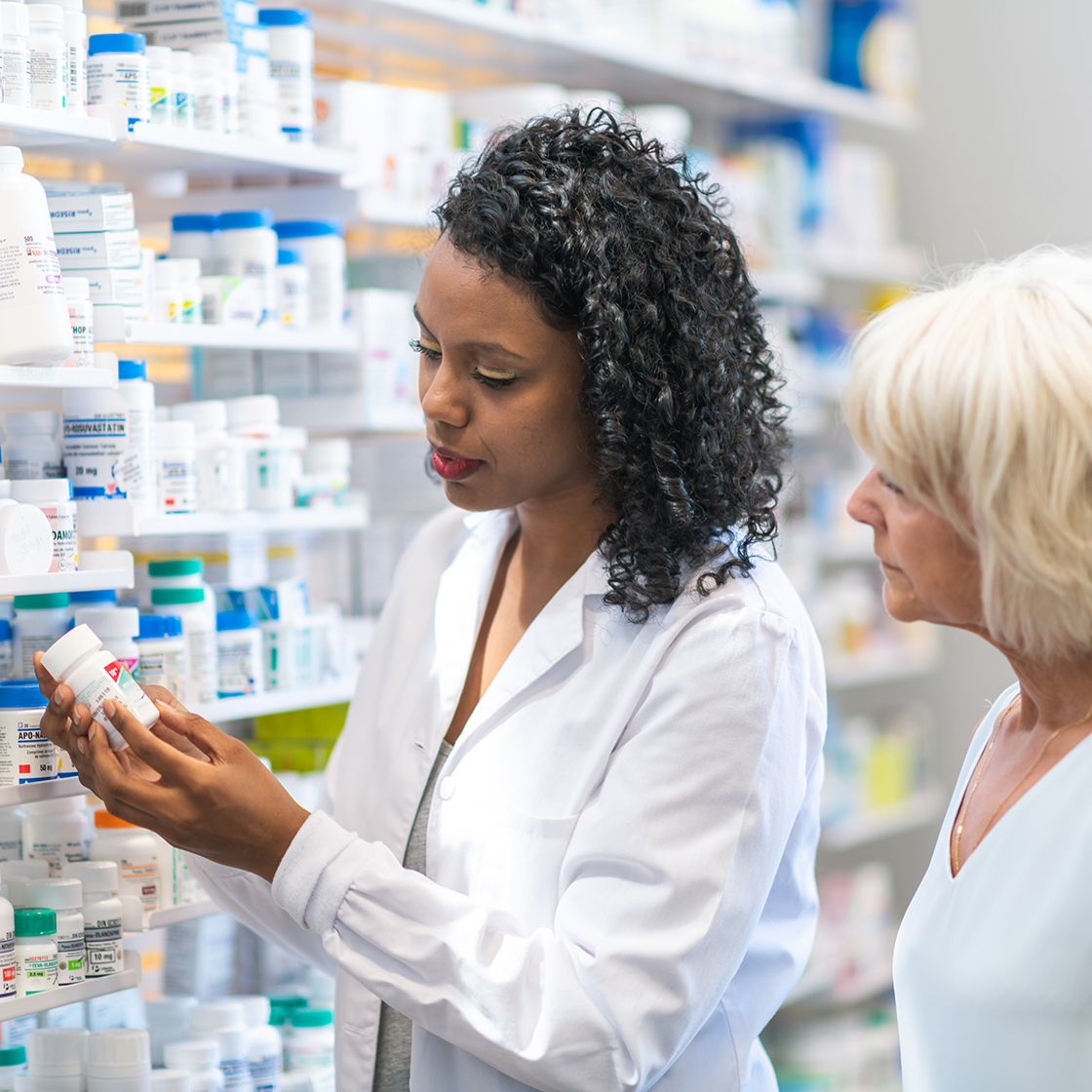 A pharmacist explains the details of a medicine to an elderly patient in a pharmacy, highlighting the importance of patient-centred packaging for informed healthcare.