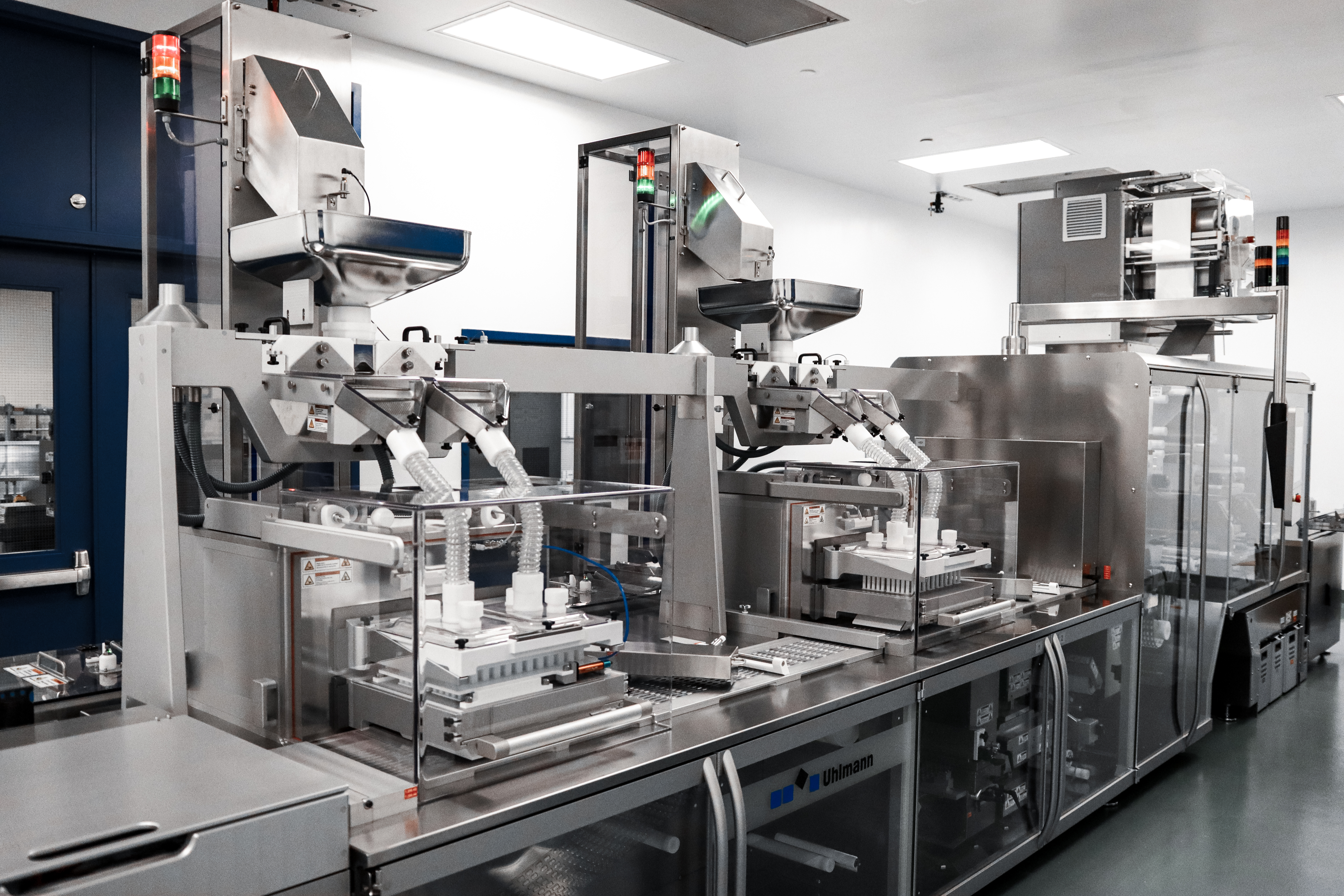A modern Uhlmann blister packaging line in a clean, industrial setting, equipped to handle solid dose medications. The machine features various modules for creating and sealing blister packs, showcasing its versatility in producing multiple blister formats.